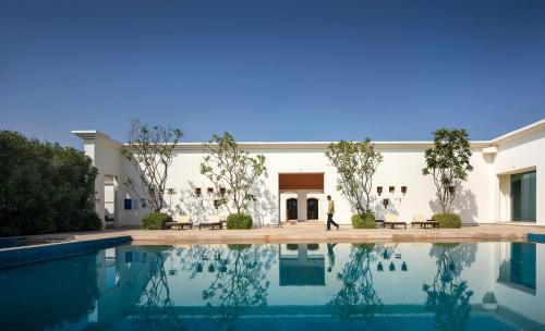 a man walks by a swimming pool in front of a building at Marasa Sarovar Premiere, Bodhgaya in Bodh Gaya