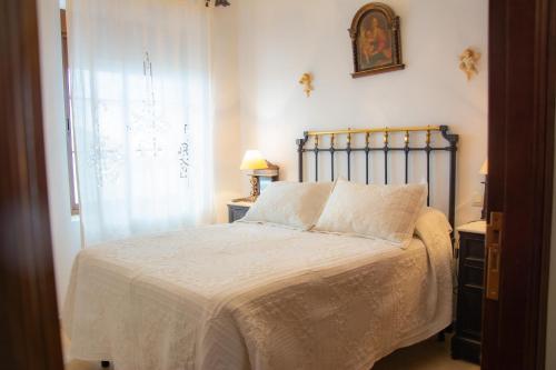 a bedroom with a bed with white sheets and a window at Casa Rural Nijata in Valencia del Mombuey
