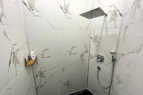 y baño de azulejos blancos con ducha y lavamanos. en Villa Einhorn: Altstadt Loft mit privater Terrasse en Goslar