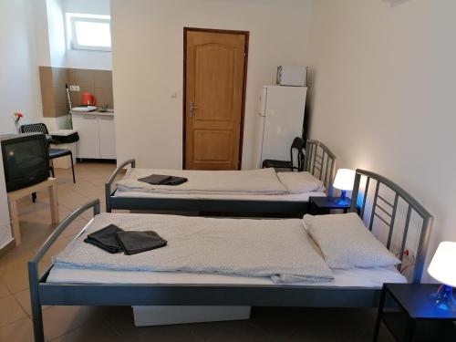 three beds in a room with a kitchen at Omega Szigetszentmiklós in Szigetszentmiklós