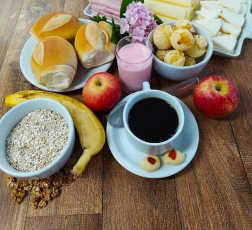 una mesa con una taza de café y un plato de comida en Hotel Oliveira 44, en Goiânia