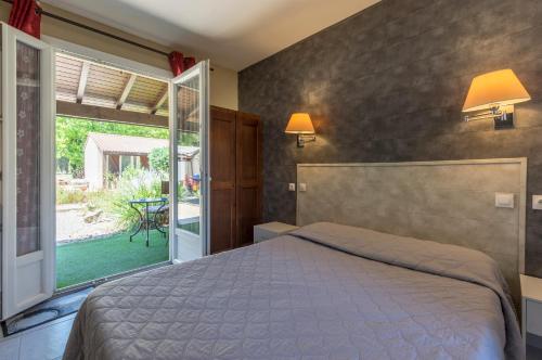 a bedroom with a bed and a large window at Logis Hotel Le Vieux Moulin in Gignac