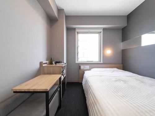 a bedroom with a bed and a desk and a window at Super Hotel Mitazono Sendai Airport in Natori