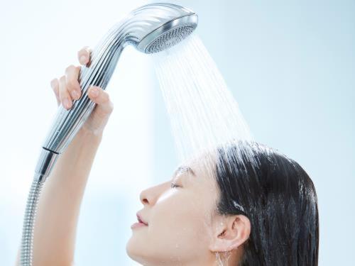 a woman is showering herself with a hair dryer at Super Hotel Mitazono Sendai Airport in Natori