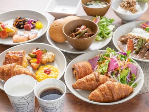 a table with plates of food and cups of coffee at Super Hotel Mitazono Sendai Airport in Natori