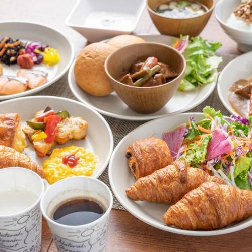 a table with plates of food and cups of coffee at Super Hotel Mitazono Sendai Airport in Natori