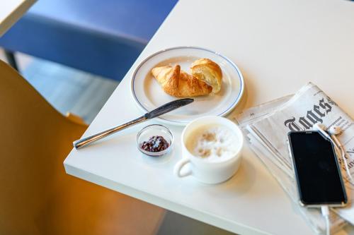 a table with a plate of food and a cup of coffee at ibis budget Zurich City West in Zürich