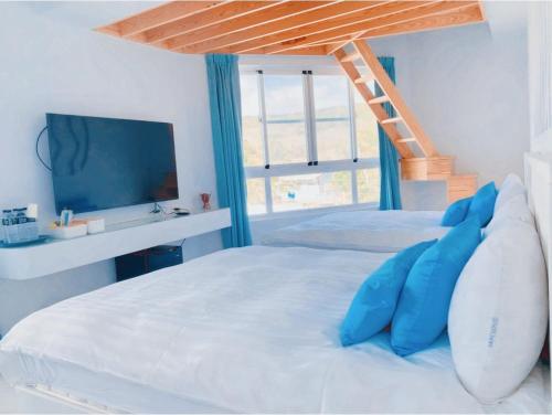 a bedroom with a bed with blue pillows and a ladder at Sky Grass in Nanwan