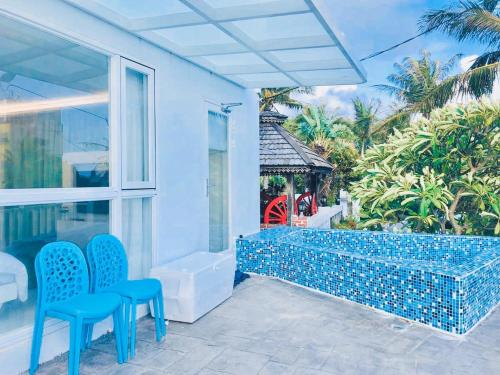 a patio with two blue chairs and a window at Sky Grass in Nanwan