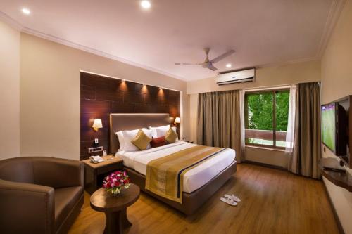 een hotelkamer met een groot bed en een bank bij Hotel Abigail Goradia's in Shirdi