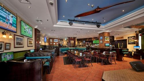 a restaurant with tables and chairs and a bar at Millennium Airport Hotel Dubai in Dubai
