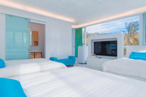 a white bedroom with two beds and a large window at Sky Grass in Nanwan
