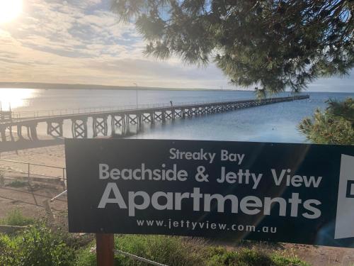 a sign in front of a beach with a pier at Beachside & Jetty View Apartment 6 - Captain's Apt in Streaky Bay