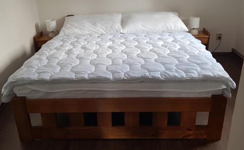 un letto con lenzuola e cuscini bianchi di Apartmán Jizerka a Kořenov
