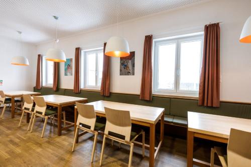 a dining room with tables and chairs and windows at Jugendherberge Bad Tölz in Bad Tölz