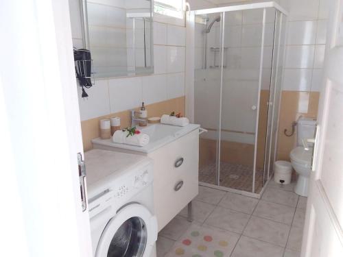 a bathroom with a sink and a washing machine at Maison chaleureuse à Le Moule avec piscine partagée in Le Moule