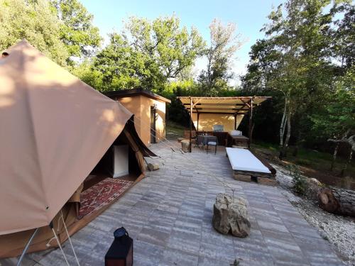 a patio with a tent and a table and chairs at Agriturismo e Glamping Serraiola Alta in Frassine