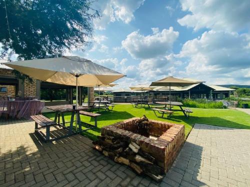 un patio con braciere, tavoli e ombrelloni di Casa Cara Resort a Parys