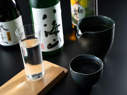 a glass of wine sitting on a table with bottles of wine at ART HOTEL Miyazaki Sky Tower in Miyazaki