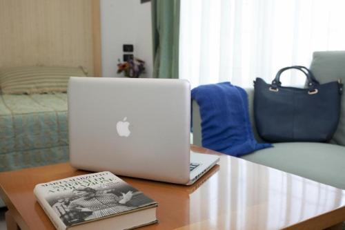 un computer portatile seduto su un tavolo con un libro di Hotel Centrale a Lido di Jesolo