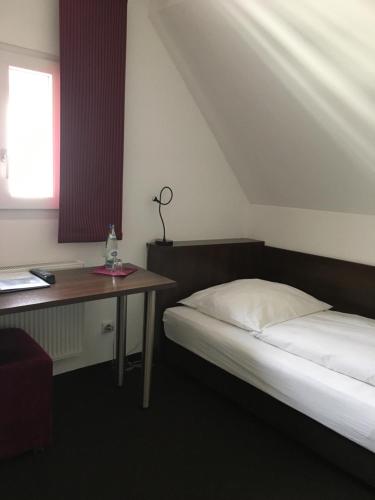 a room with a bed and a desk and a bed sidx sidx sidx at Hotel Bergbauer mit Late-Self-Check-IN in Neuburg an der Donau