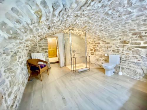 a bathroom with a stone wall and a toilet at La Maison des Vendangeurs - TABLE D'HÔTES le soir du jeudi au dimanche- Jacuzzi - Balnéo SPA - ACCES PISCINE pour toutes les chambres sauf STUDIO COQUET- Piscine de mai à mi-octobre in Martignargues