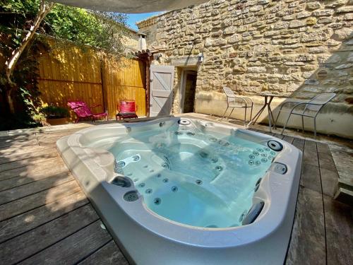 a jacuzzi tub sitting on a deck at La Maison des Vendangeurs - TABLE D'HÔTES le soir du jeudi au dimanche- Jacuzzi - Balnéo SPA - ACCES PISCINE pour toutes les chambres sauf STUDIO COQUET- Piscine de mai à mi-octobre in Martignargues
