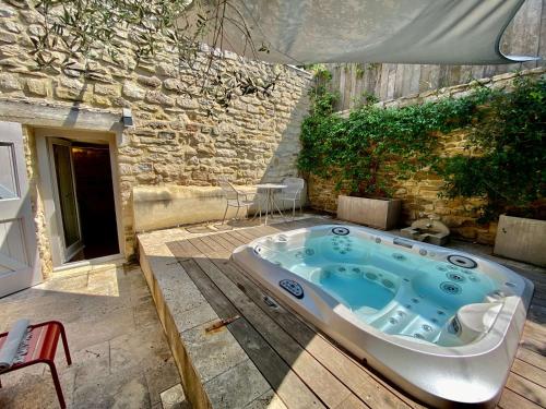 a jacuzzi tub in a courtyard with a building at La Maison des Vendangeurs - TABLE D'HÔTES le soir du jeudi au dimanche- Jacuzzi - Balnéo SPA - ACCES PISCINE pour toutes les chambres sauf STUDIO COQUET- Piscine de mai à mi-octobre in Martignargues