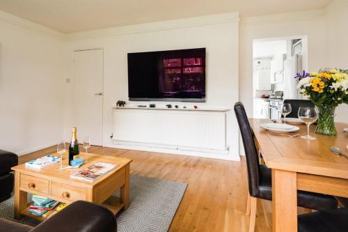 ein Wohnzimmer mit einem Esstisch und einem TV in der Unterkunft Bright and Spacious Philbeach Garden Apartment in London
