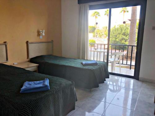 a hotel room with two beds and a balcony at Carina Hotel Apartments in Ayia Napa