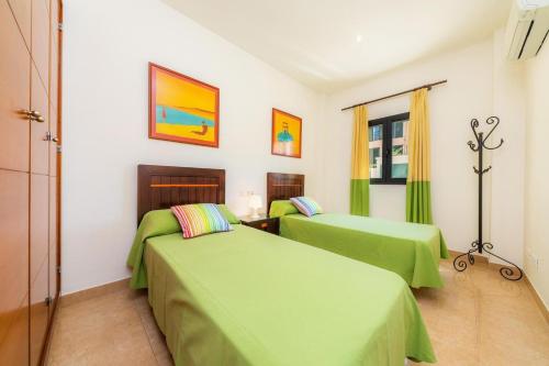 two beds in a room with green sheets at Can Joan in Pollença