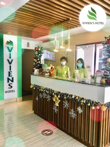 two people wearing masks standing at a counter in a store at Vivien's Hotel in Mactan