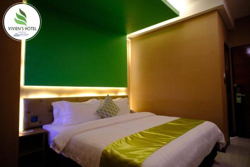 a bedroom with a green wall and a bed at Vivien's Hotel in Mactan