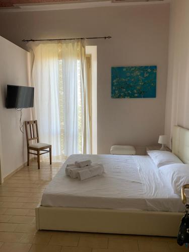 a bedroom with a bed and a chair and a window at La Mela Rosa in Valentano