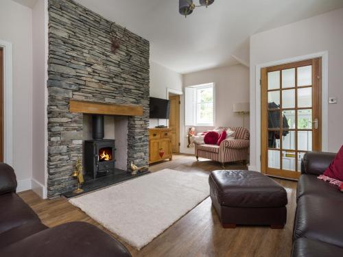 a living room with a stone fireplace and a couch at Fellside Lodge in Windermere