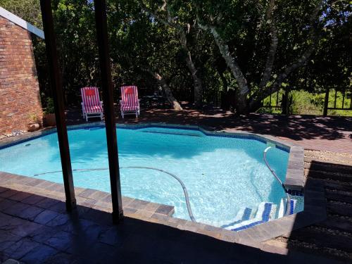 a swimming pool with two lawn chairs in it at Protea Lodge and Cottage- NO LOADSHEDDING in Port Elizabeth