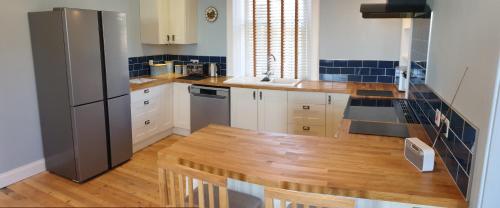 a kitchen with a refrigerator and a wooden floor at Harbour Lights - Spectacular Sea Views in Crail