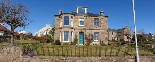 an old house with a fence in front of it at Harbour Lights - Spectacular Sea Views in Crail
