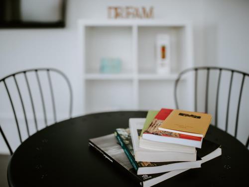 a stack of books on a black table with chairs at DREAMS HOUSE in Faro