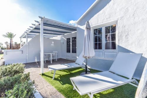 a patio with two chairs and an umbrella at Villas New Lanzasuites in Playa Blanca