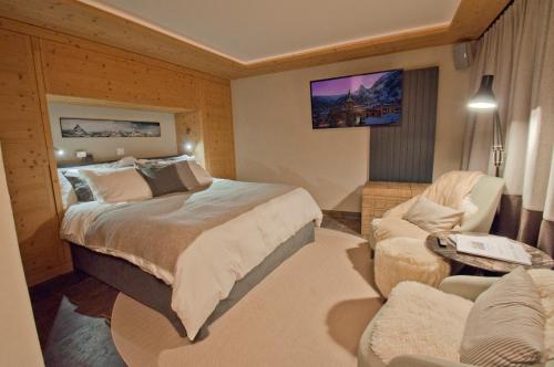 a hotel room with a bed and a chair at Twin Peak apartment at Nevada prime in Zermatt