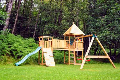un parque infantil de madera con tobogán y estructura de juegos en Cosy & compact Rowan Lodge no4 en Killin