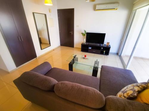 ein Wohnzimmer mit einem Sofa und einem TV in der Unterkunft Promenade Breeze City Apartment in Larnaka