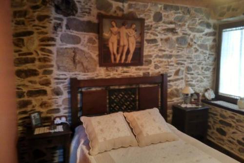 1 dormitorio con cama y pared de piedra en Casa da Penisquela, en O Barco de Valdeorras