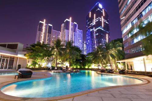 a large swimming pool with a city skyline at night at Wyndham Casablanca Jakarta in Jakarta