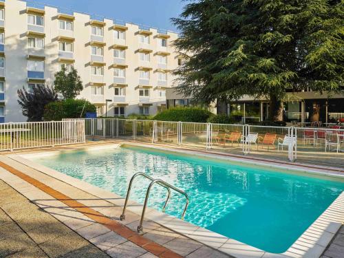 a large swimming pool in front of a building at Novotel Massy Palaiseau in Palaiseau