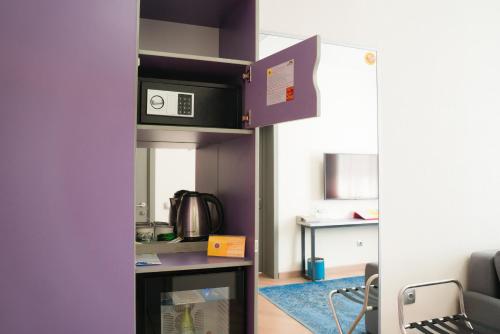 a room with a kitchen with a microwave on a shelf at City Hotel Shymkent in Shymkent