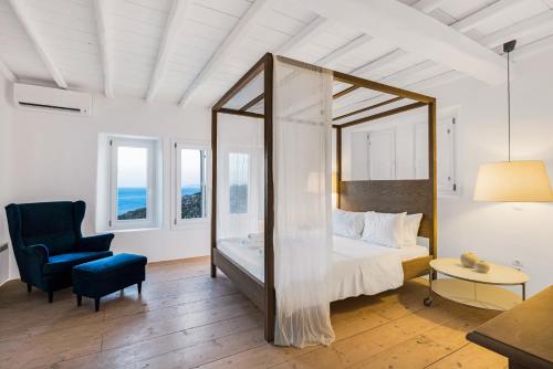 a bedroom with a bed and a chair and a mirror at Villa Artisti Mykonos in Agrari