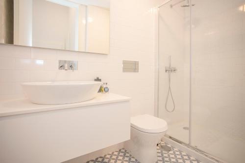 a white bathroom with a sink and a shower at Liiiving in Porto - City View Apartments in Porto