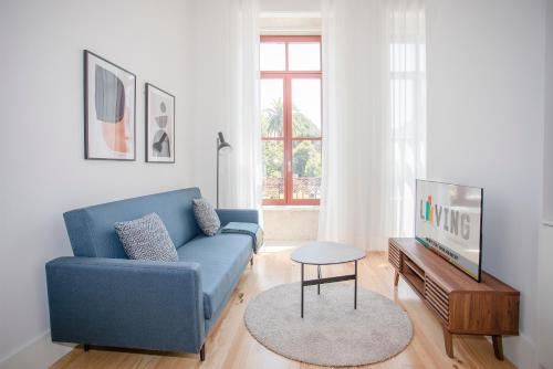 a living room with a blue couch and a tv at Liiiving in Porto - City View Apartments in Porto